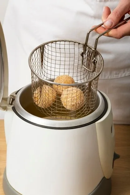 Primer plano de una mano colocando croquetas para cocinar